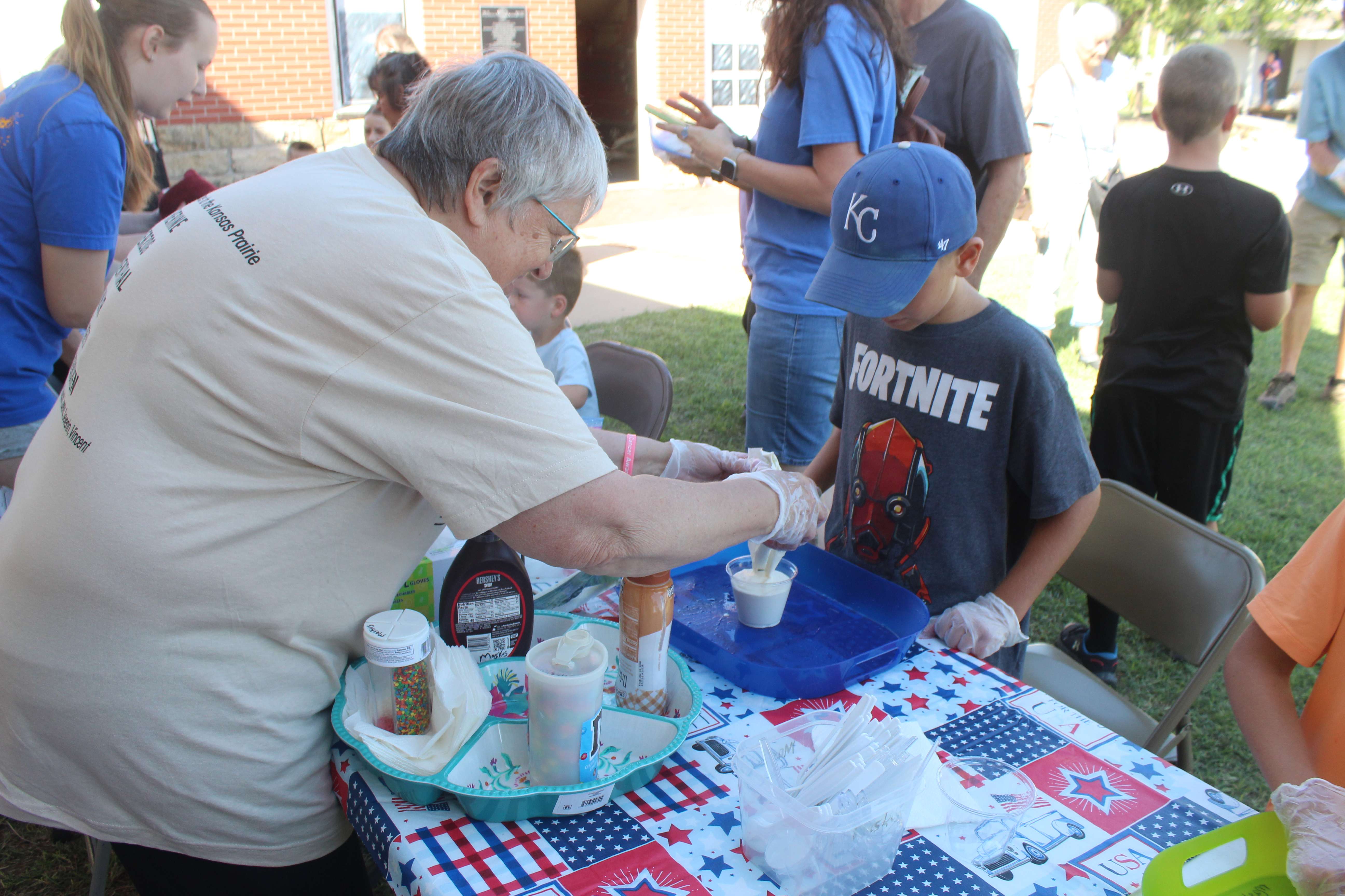 Donna Maskus, volunteer, helps a boy with his homemade ice cream Saturday at Kinderfest.&nbsp;Photo by Cristina Janney/Hays Post