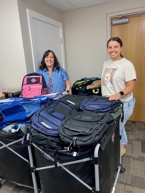 Laura Shoaff and Macey Pfeifer with First Call for Help of Ellis County stand with backpacks that have been stuffed and are ready for distribution Aug. 6. These are just the first few of the more than 600 backpacks that First Call will be preparing this year. Courtesy Photo<br>