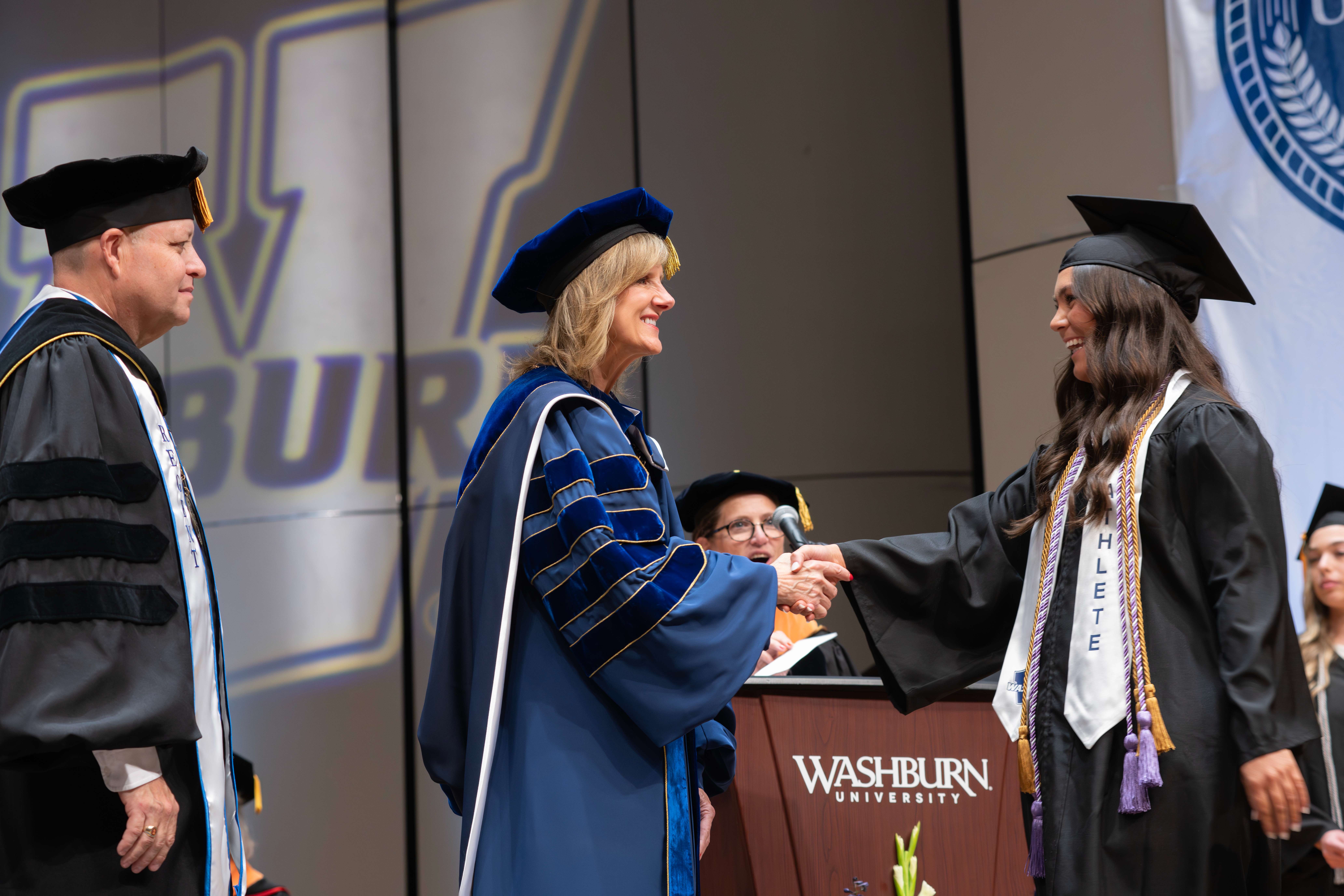 Washburn University President Dr. JuliAnn Mazachek congratulates a graduate during commencement ceremonies as students celebrate the culmination of their academic achievements. Photo courtesy of Washburn University.