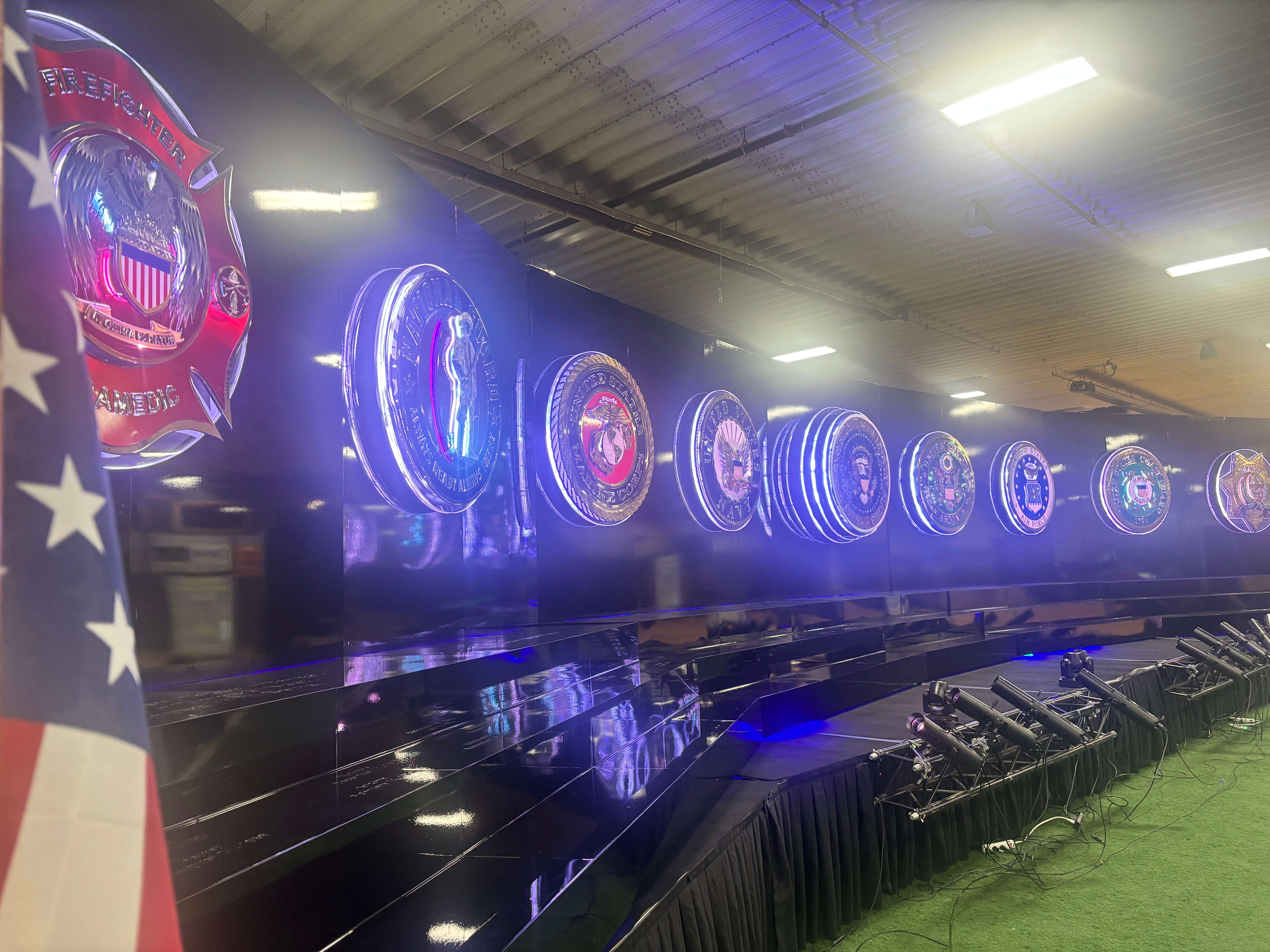 Large illuminated service emblems line the Wall of Heroes exhibit during a Patriot Thunder presentation in North Platte. Organizers say the traveling display is designed to honor military members, first responders and the freedoms their service helps protect. (Allison Peck | The Post)