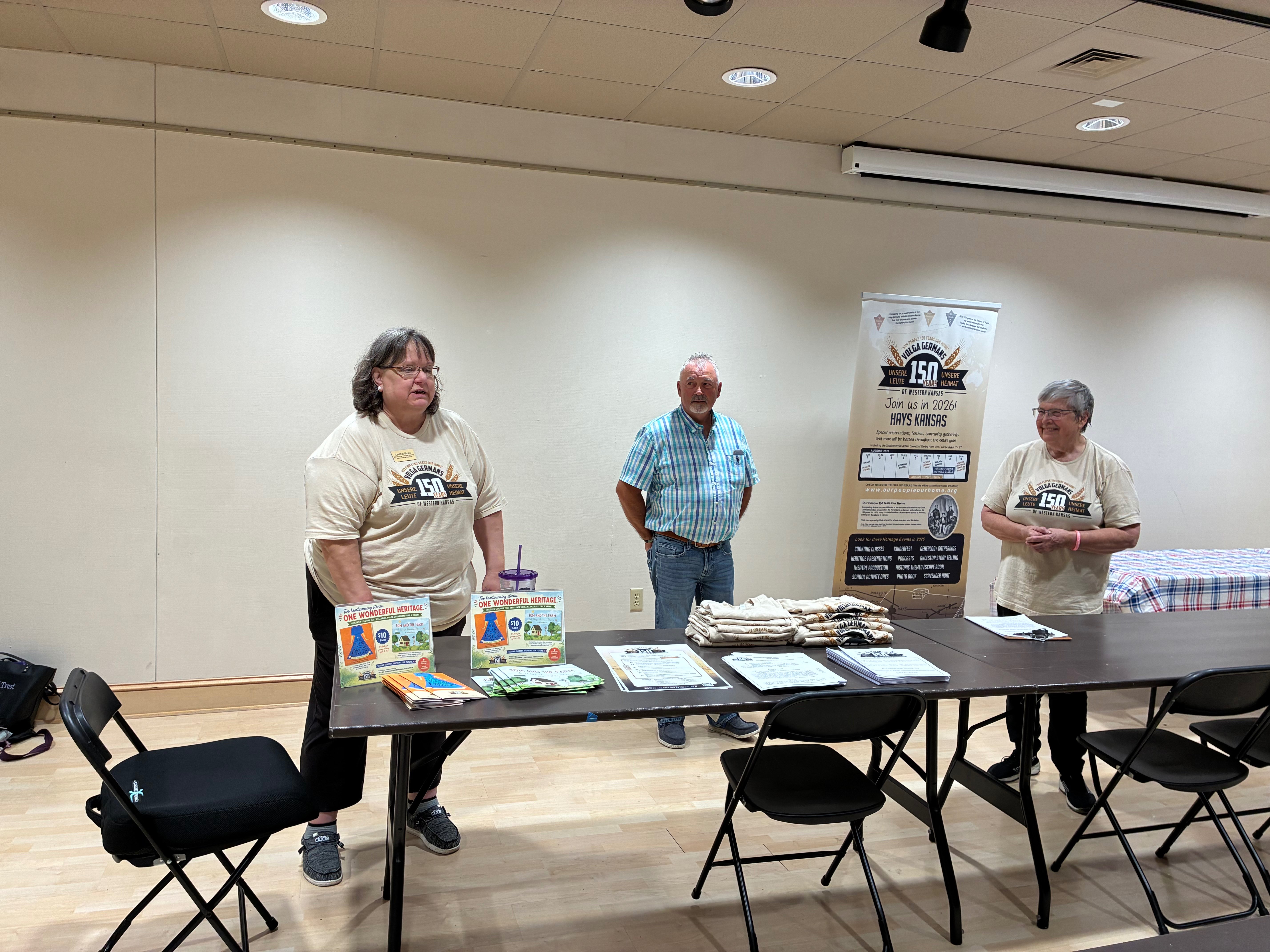 Administrative assistant for the Ellis County Historical Society Cynthia Stone, left, and board member for the Ellis County Historical Society, Donna Maskus, right, introducing Volga German and Ellis County Commissioner Neal Younger, middle, at the Sesquicentennial Cooking Demo. Photo by Alin Hett/Hays Post