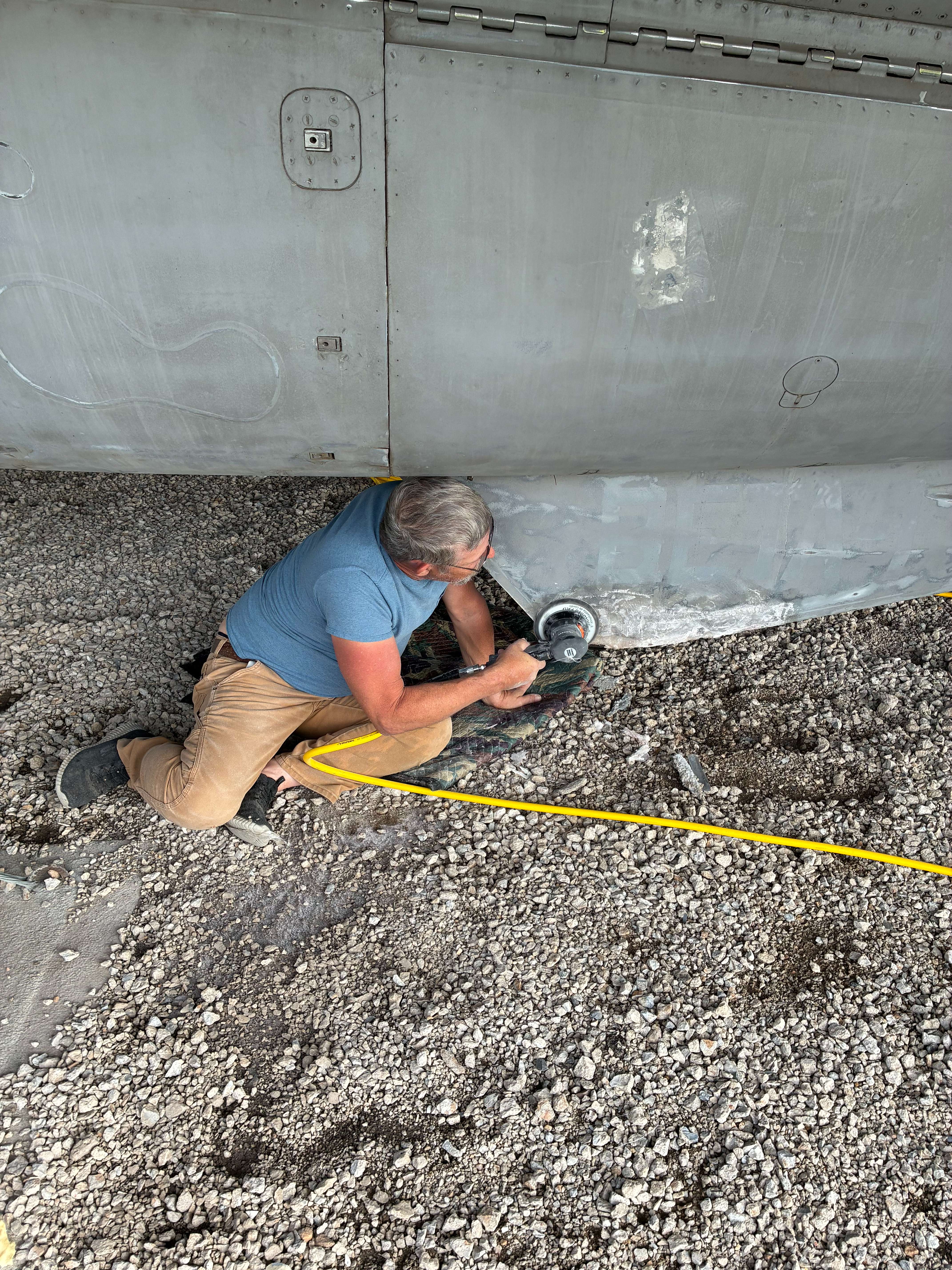 Michael Martin, AT1 aviation electronics technician, callsign “Magic” sanding the bottom of the F14 Tomcat, getting the fighter jet ready for re-painting. Photo by Alin Hett/Hays Post