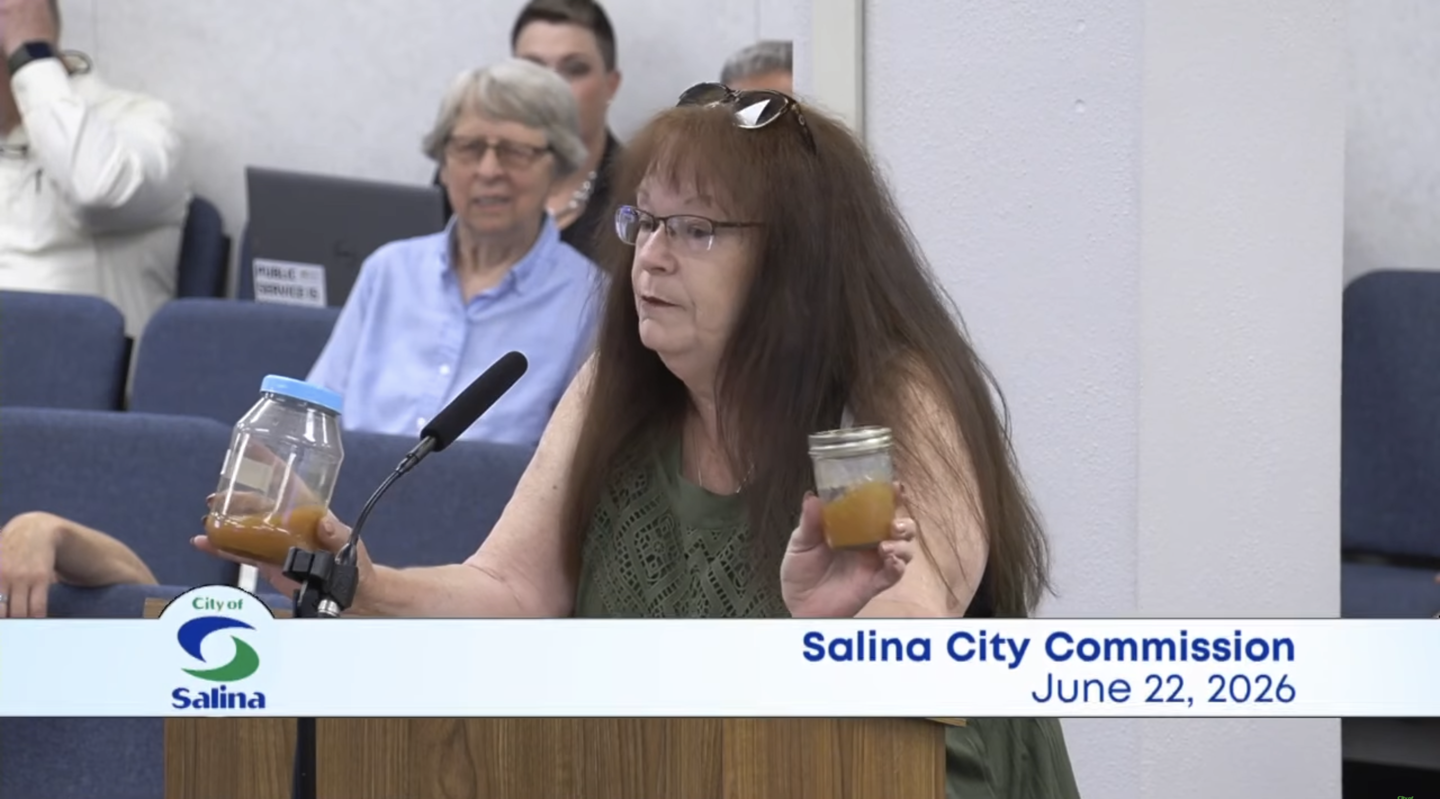 Dover Drive resident, Sheree Spratlen shows two containers of discolored water Salina Commissioners on June 22 - Screenshot of Salina City Commission public meeting 