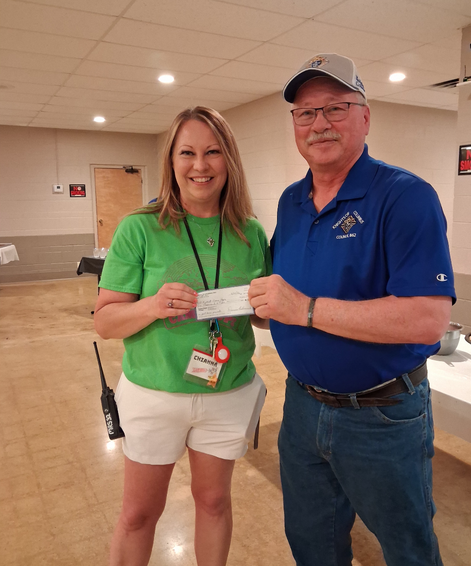 Chianna Henkel, camp director at Camp Hope, accepts a donation from Knights of Columbus Grand Knight David Dreiling during a free lunch at the Columbus Club in Great Bend on Monday.