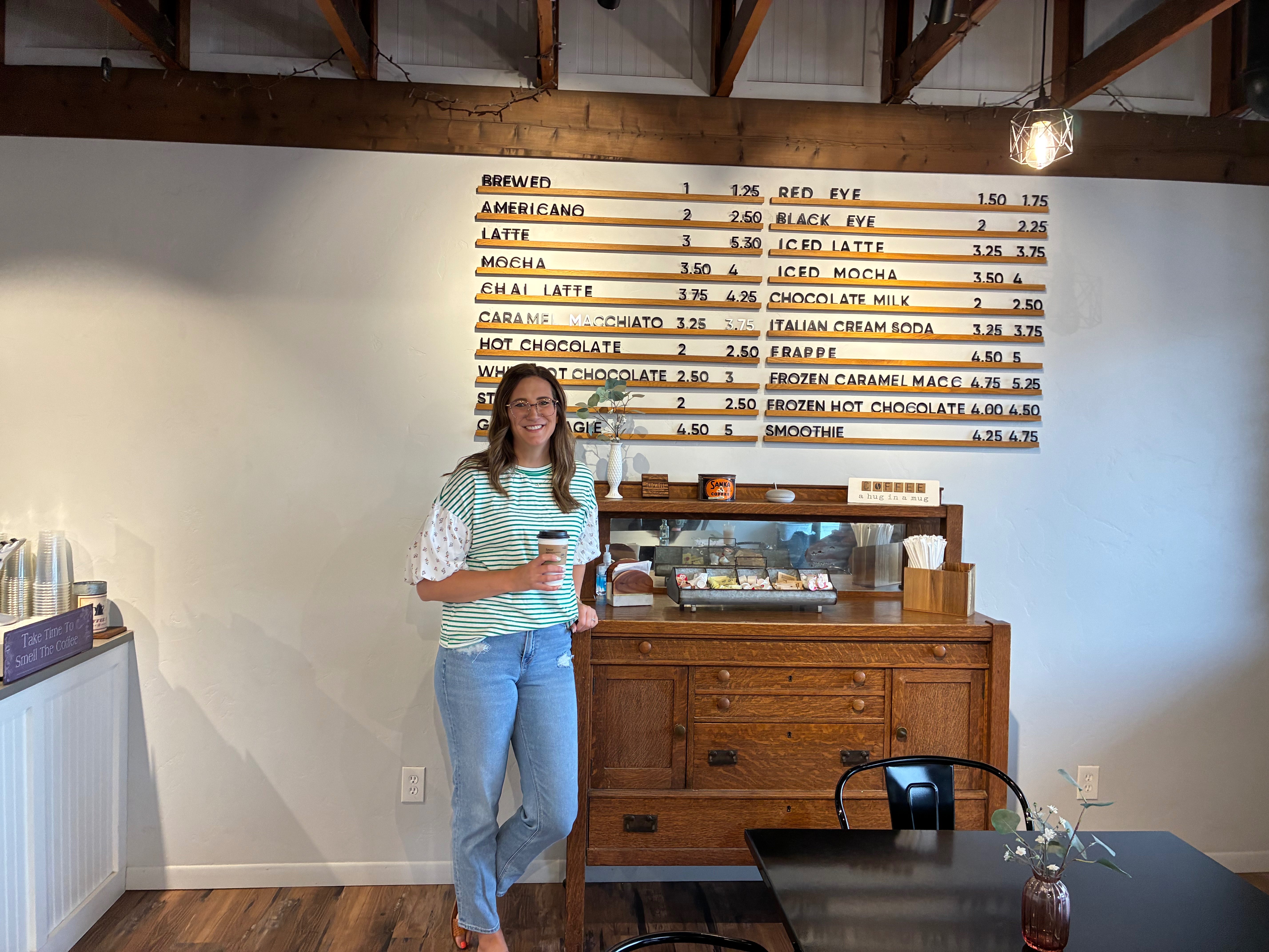 New manager Bailey Belisle stands with a cup of coffee in her hand inside The Well-Center for Hope. Photo by Alin Hett/Hays Post&nbsp;