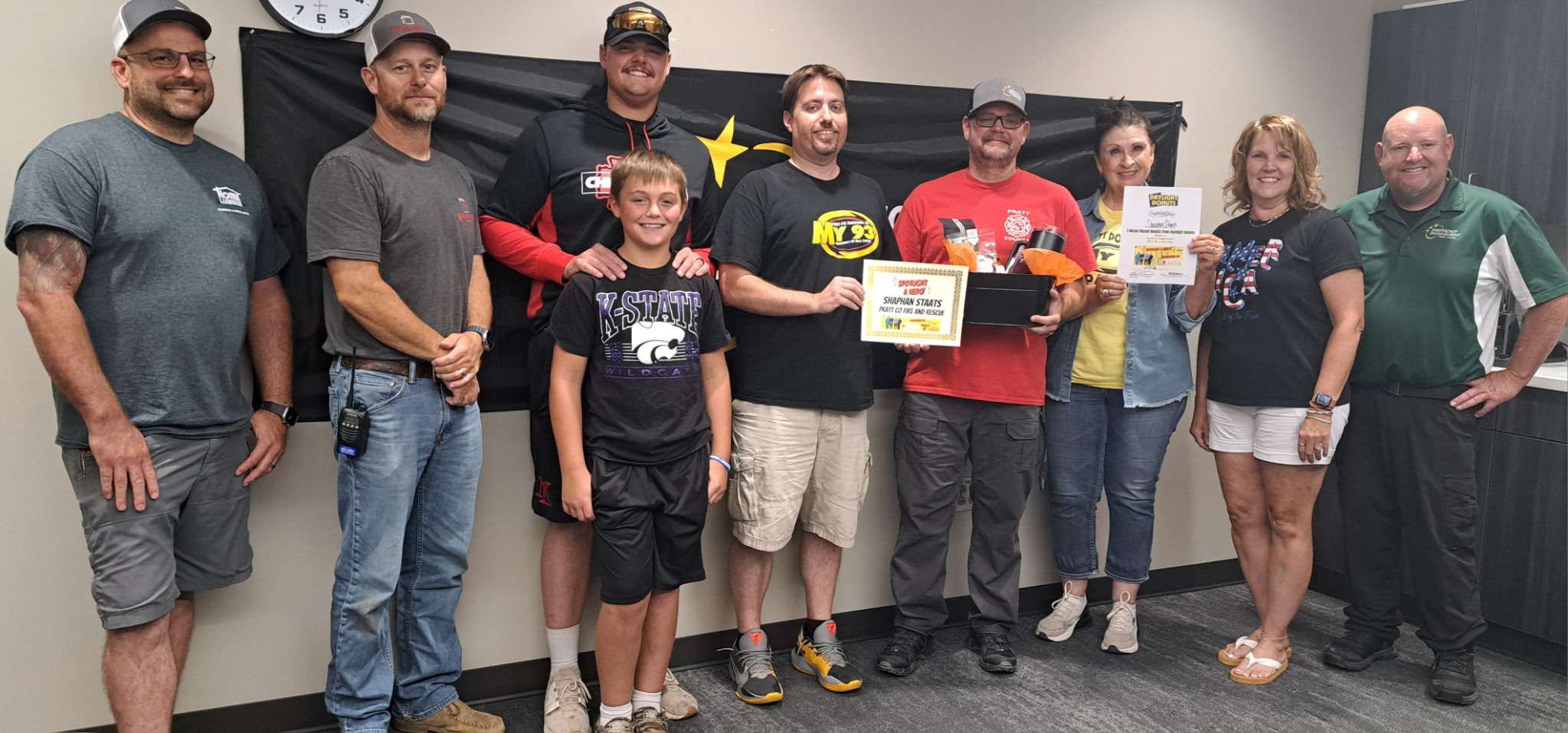 Shaphan Staats, center in red, chaplain with Pratt County Fire and Rescue, receives the June First Responder of the Month award from Daren Dunn and Colleen Floyd with Eagle Media. Staats was joined by members of the Pratt County Fire and Rescue team and family members for the presentation. The award is presented by Eagle Media and PrairieStar Health Center. (Hutch Post Photo)