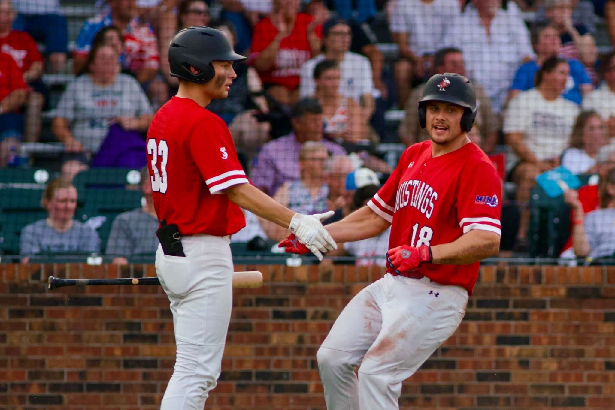 Isiah Kettler (33) celebrates with Benedictine's Carson Hintz (18) as he crosses home plate in the second inning/ Photo by Darren Doyle