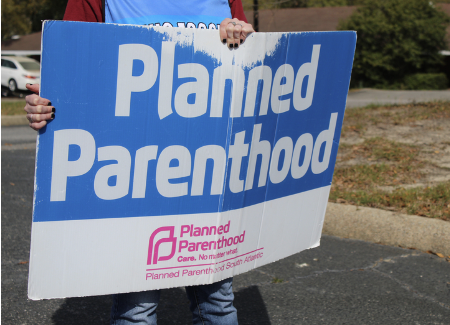 A volunteer clinic escort holds a sign outside a Planned Parenthood clinic in Columbia, South Carolina, on March 28, 2025. (Photo by Skylar Laird/SC Daily Gazette)