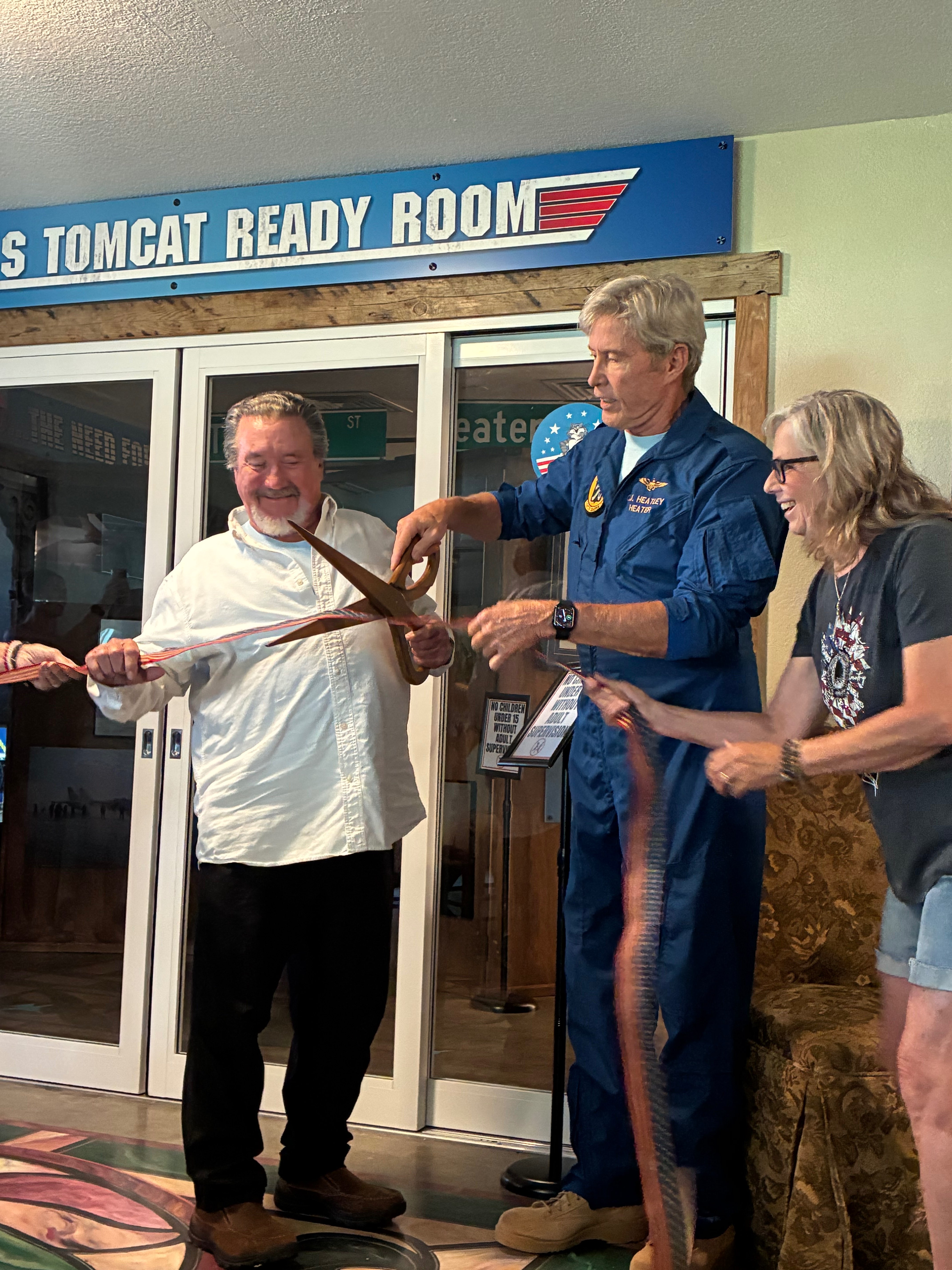 CJ "Heater" Heatley cutting the opening ribbon next to Bill Spires, left and Tami Green, right, to the Rosie's TOMCAT Ready Room. Photo by Alin Hett/Hays Post