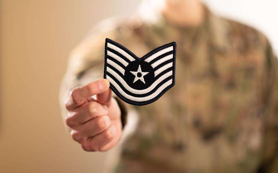 An airman poses for a photograph holding a technical sergeant stripe. (Mark Herlihy/U.S. Air Force)