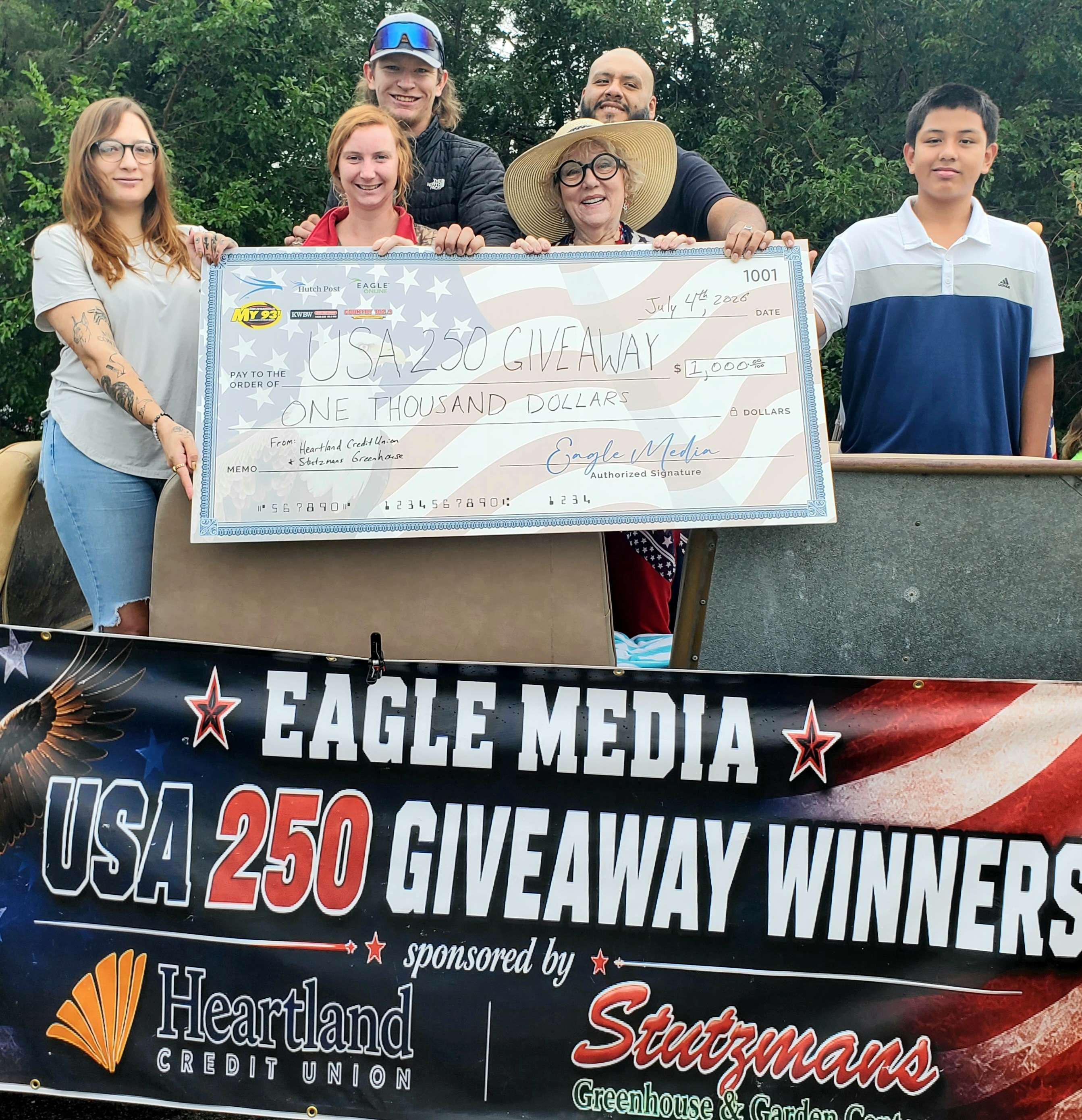 $1,000 Winners: Madison Carithers (far left), Brennon Good (hat and sunglasses), Marilyn Graham (right of center, holding check) and Antonio Blancarte (right of center in back). Not pictured: Deb McNew and Robert Tibbits.