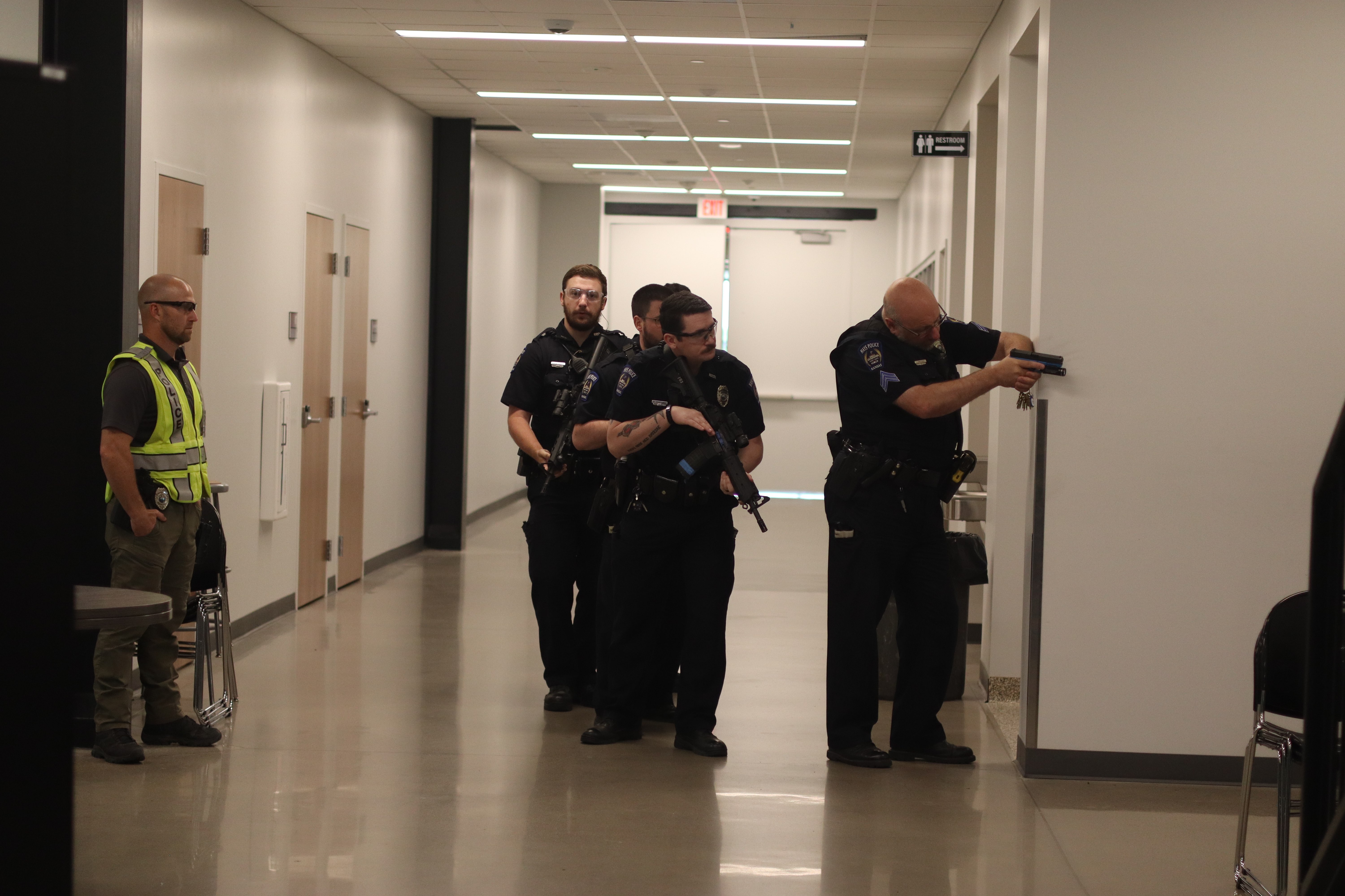 Hays Police Department officers clear a hallway during an active shooter training exercise at Hays High School while supervisors observe the response tactics.<br>
