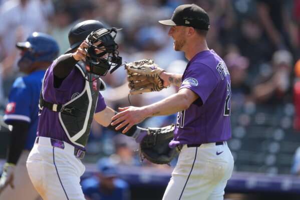 Colorado Rockies catcher Brett Sullivan, left, hugs starting pitcher Kyle Freeland, right, after Kansas City Royals' Tyler Tolbert flew out to end a baseball game Sunday, Aug. 2, 2026, in Denver. (AP Photo/David Zalubowski)
