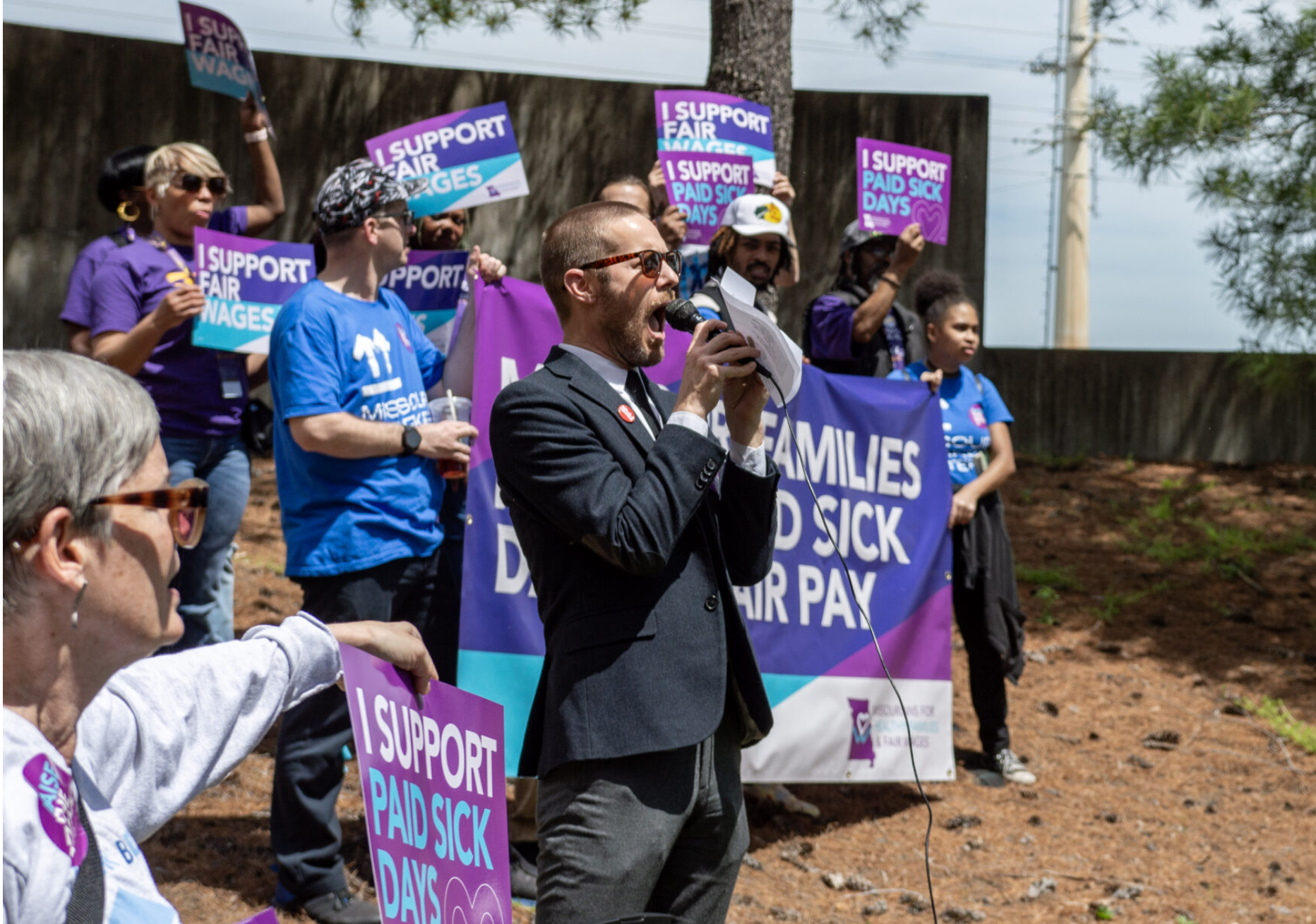  Daniel Tucker, a leader with the Missouri Workers Center, teaches chants customized to an initiative petition to raise the minimum wage and mandate paid sick leave outside of the Secretary of State’s office building in Jefferson City in May 2024 (Annelise Hanshaw/Missouri Independent).