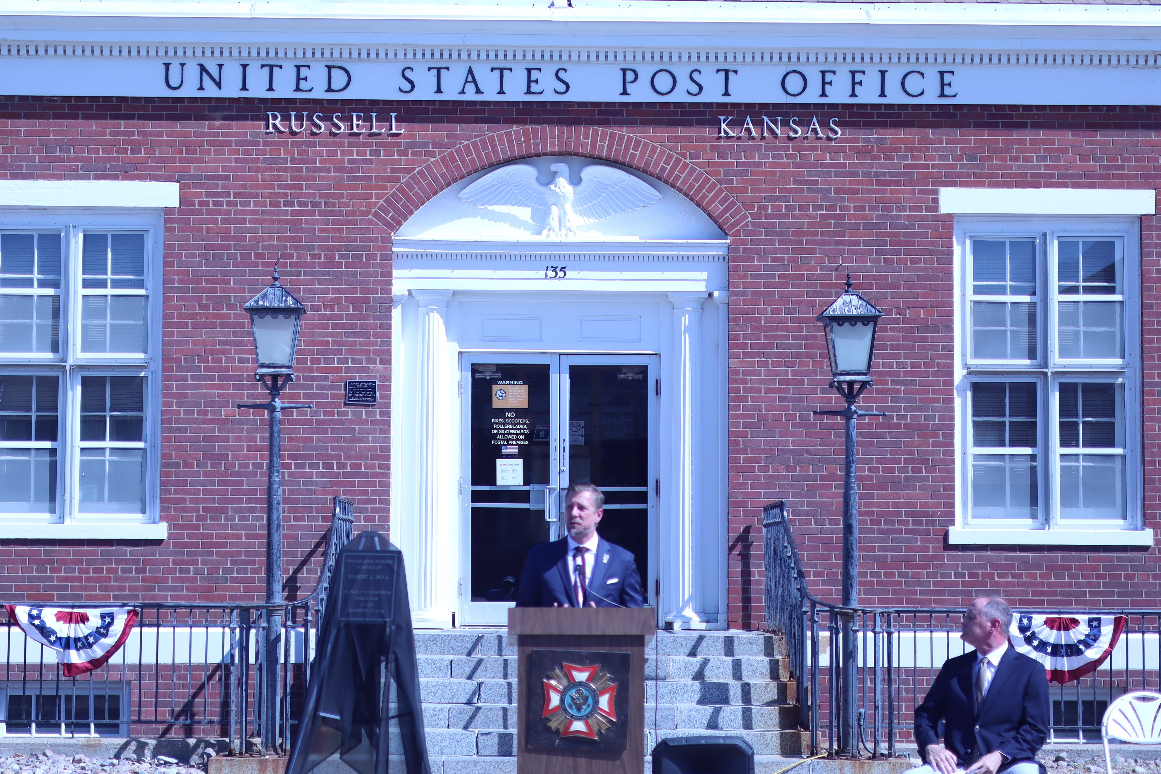 Jeremie Six, district manager for the United States Postal Service, speaks during the ceremony honoring Bob Dole.<br>