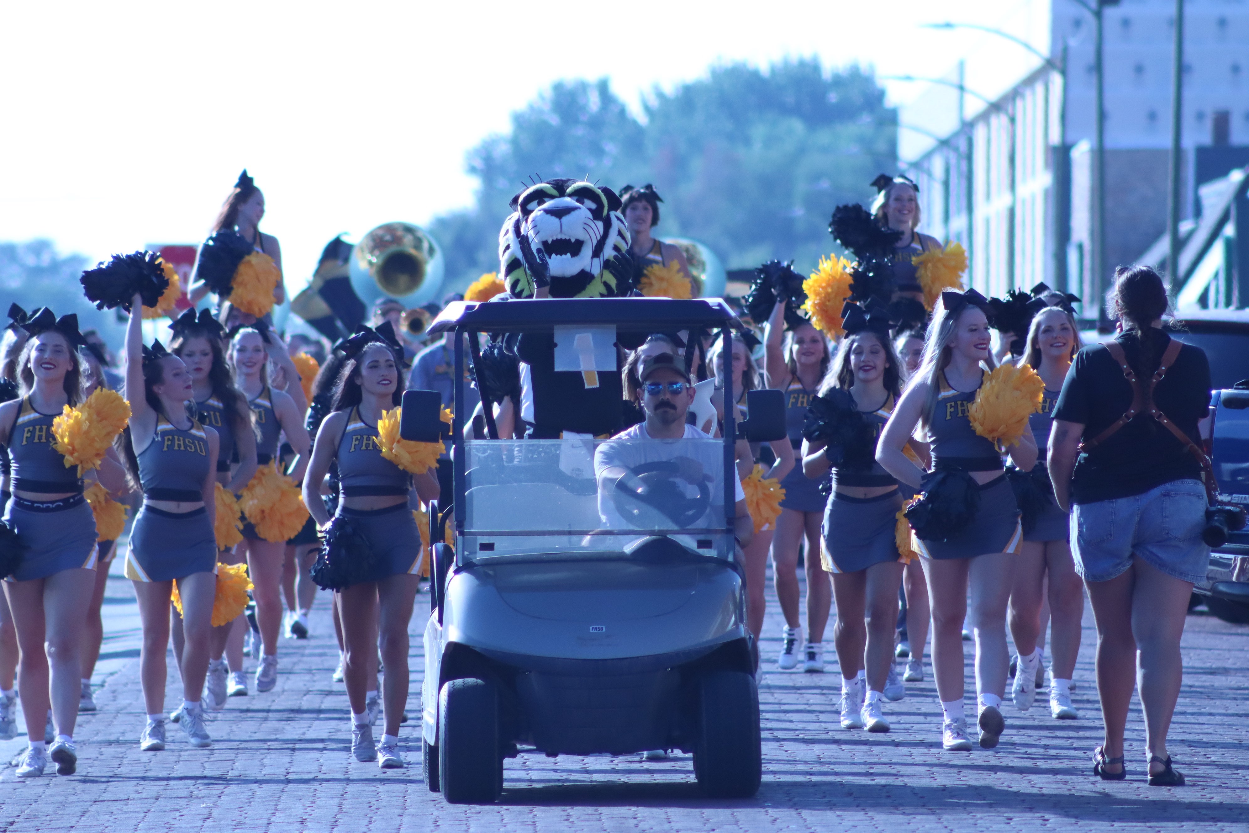 FHSU cheerleaders lead students as they make their way toward downtown Hays behind a golf cart featuring the FHSU Tiger during March 2 Main 2026. Photo by Alin Hett/Hays Post.&nbsp;<br>