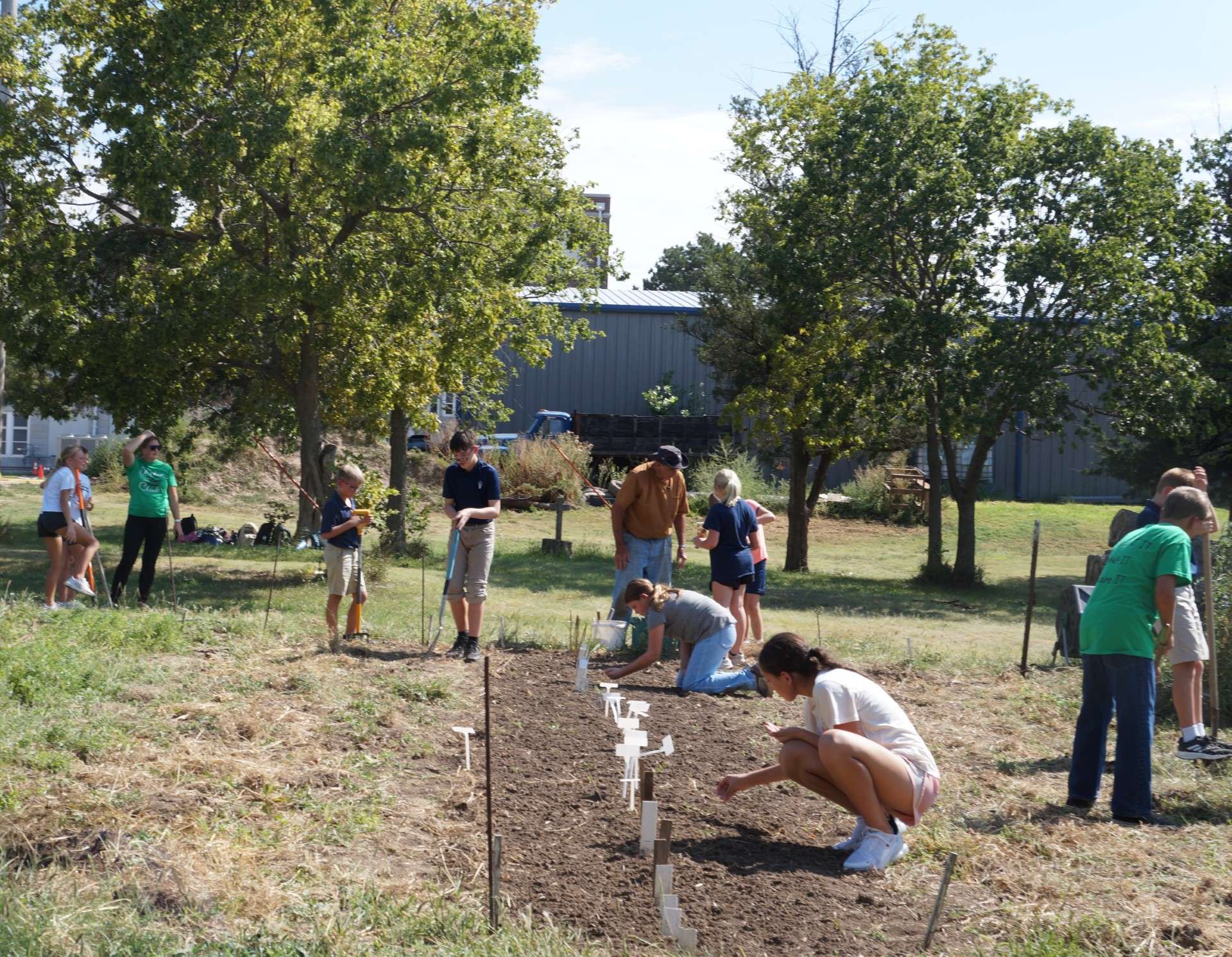 Six graders in the Garden Club at Thomas More-Prep Marian Junior High School work in their garden during a club meeting on Aug. 26. At left in green shirt is sponsor Melissa Pinkney. In the center, wearing a hat, is the other sponsor, Randy Brull. Photo by Linn Ann Huntington