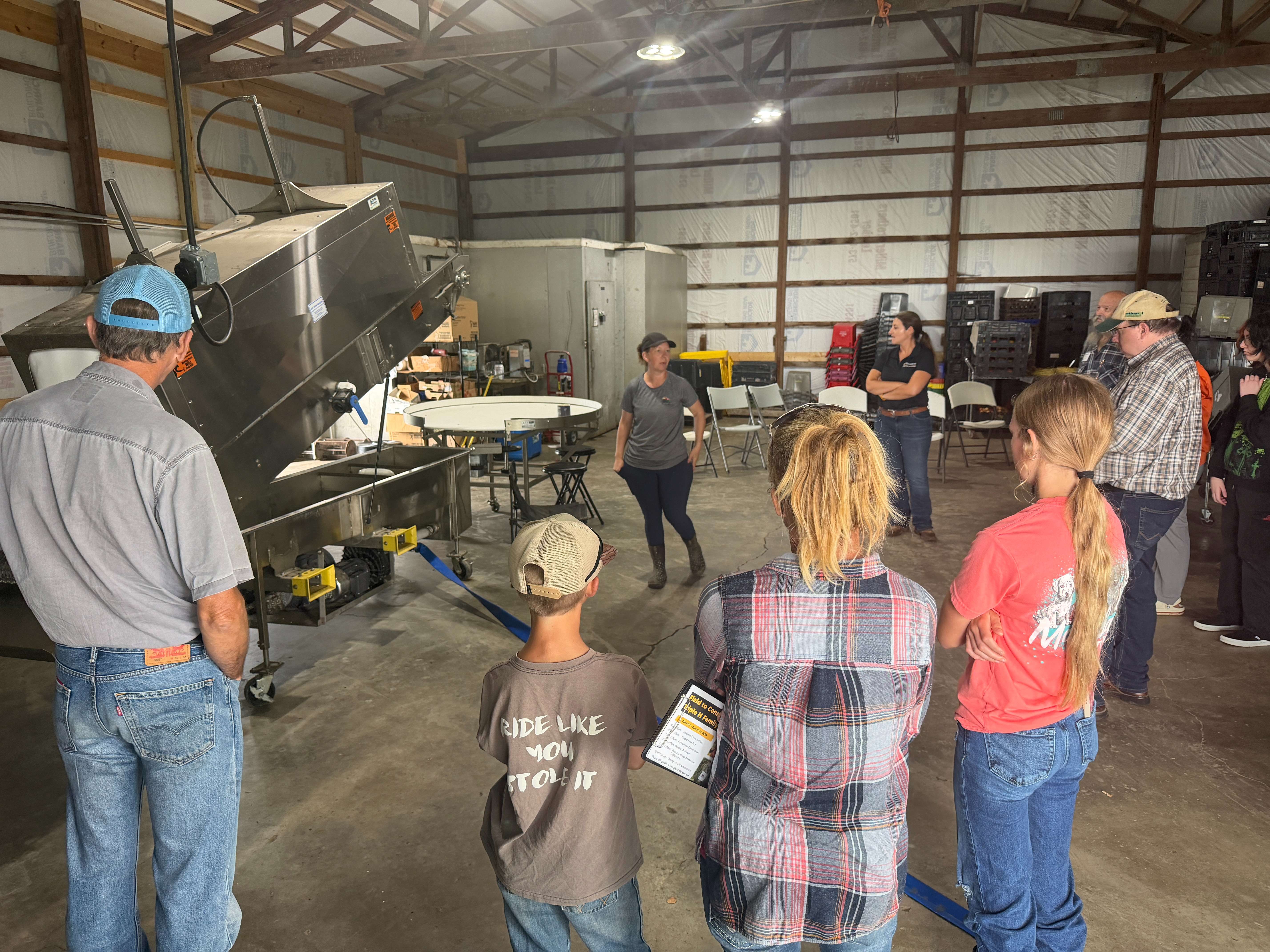 Kim Tennill, Owner of Triple H Family Farms, explains the produce washer to attendees and how it has improved their efficiency in processing produce for the market.