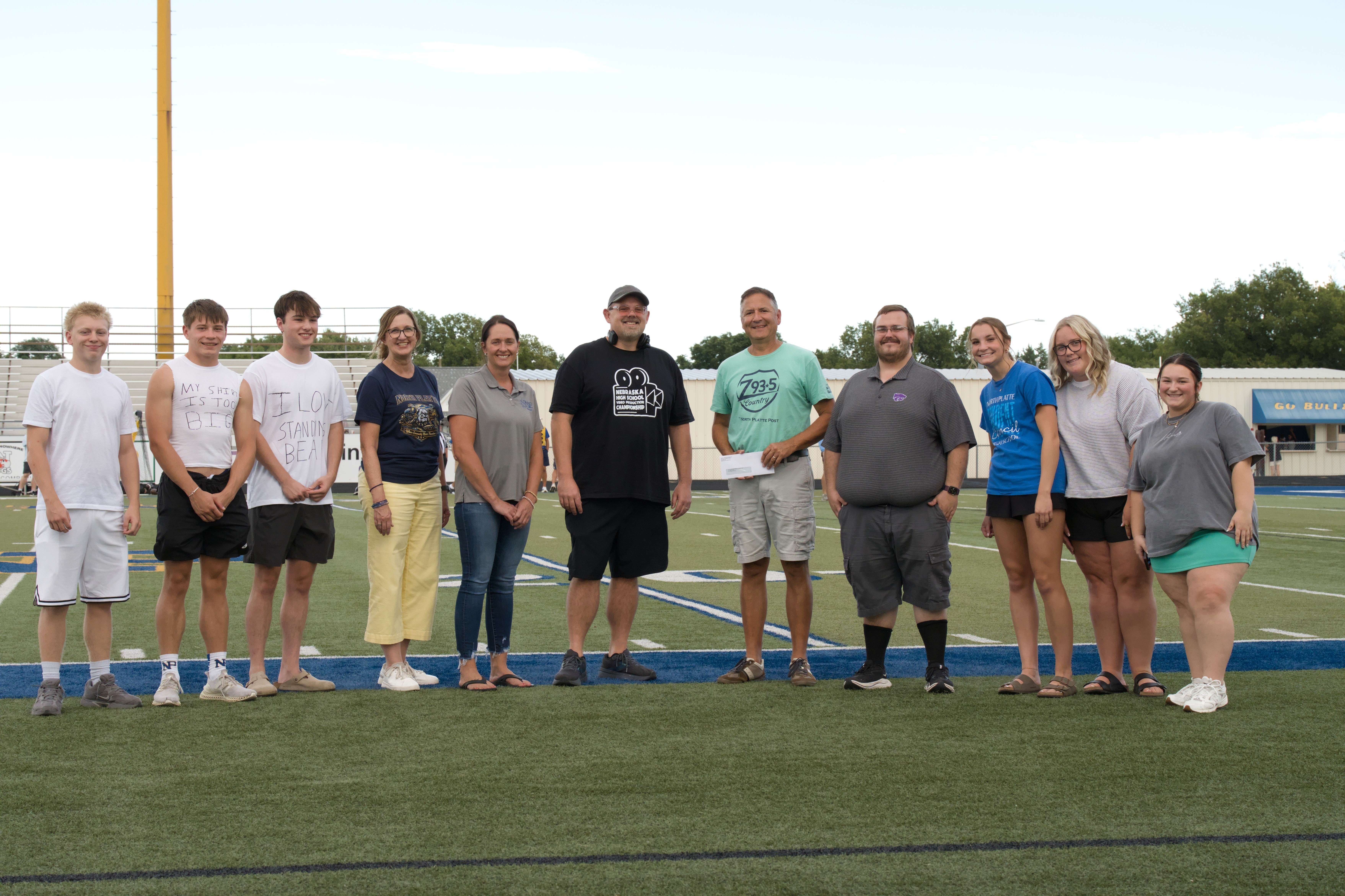 Eagle Radio and Schmidt Foundation representatives join North Platte High School students and staff at Bauer Field following a $20,000 donation to the North Platte Public Schools Foundation to support the expansion of the Bulldog Productions Creative Lab. (Courtesy Photo)