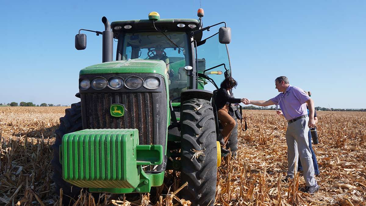 K-State Vice President for Research Hans Coetzee helps a tour participant out of a tractor at the Flickner Innovation Farm. (Courtesy K-State Research and Extension)
