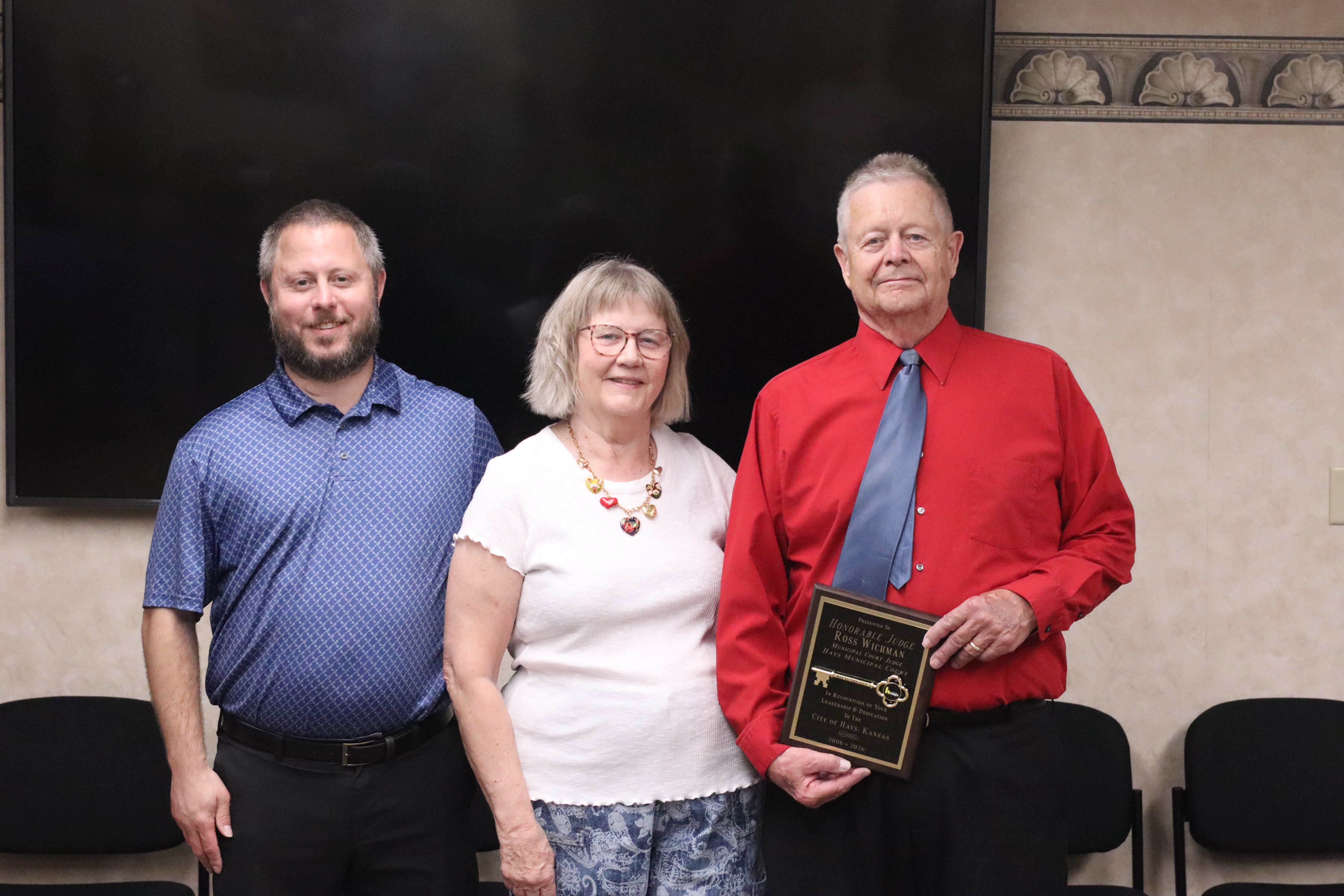 Judge Ross Wichman stands with his family holding a "Key to the City" at his retirement ceremony. From Left: Ross "Rowdy" Wichman Jr., Gayla Wichman, Judge Ross Wichman. Photo by Alin Hett/Hays Post
