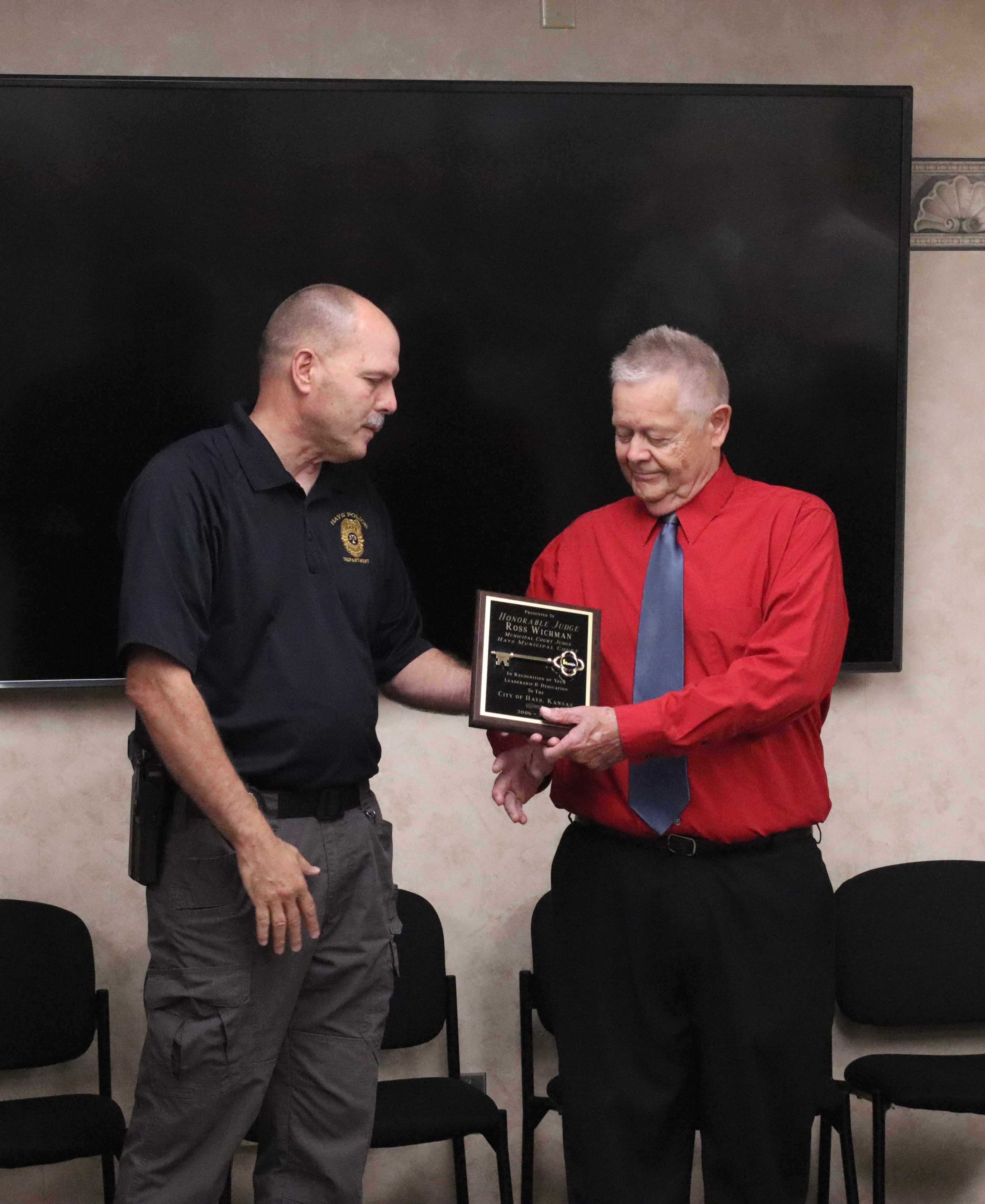 Hays Police Chief Don Scheibler handing the "Key to the City" to Judge Ross Wichman during his retirement ceremony. Photo by Alin Hett/Hays Post.&nbsp;