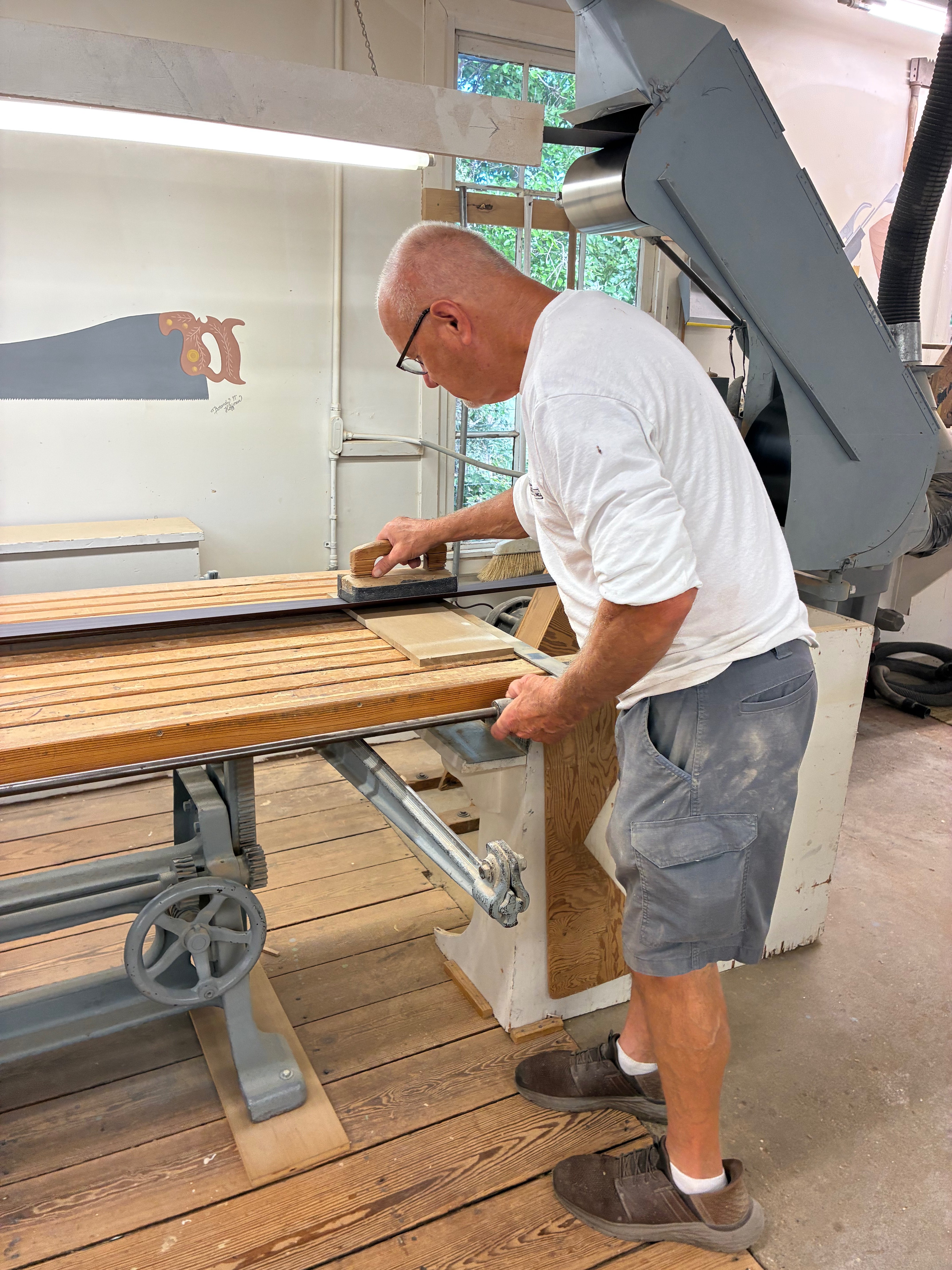 Dennis Braun smooths a piece of wood with a sanding block inside the Hays Planing Mill workshop.<br>