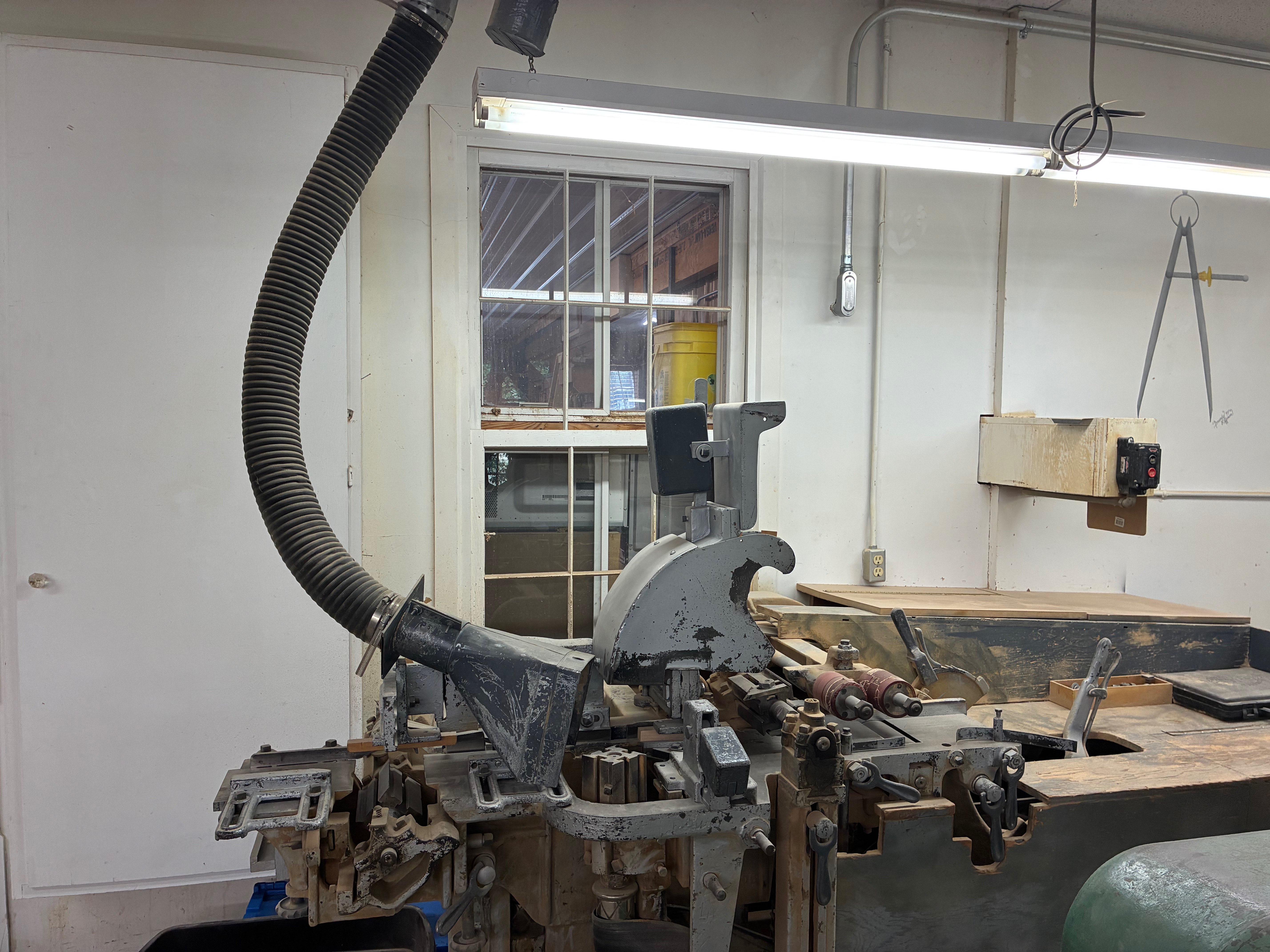 A specialized woodworking machine connected to a dust-collection system sits inside the Hays Planing Mill workshop.<br>
