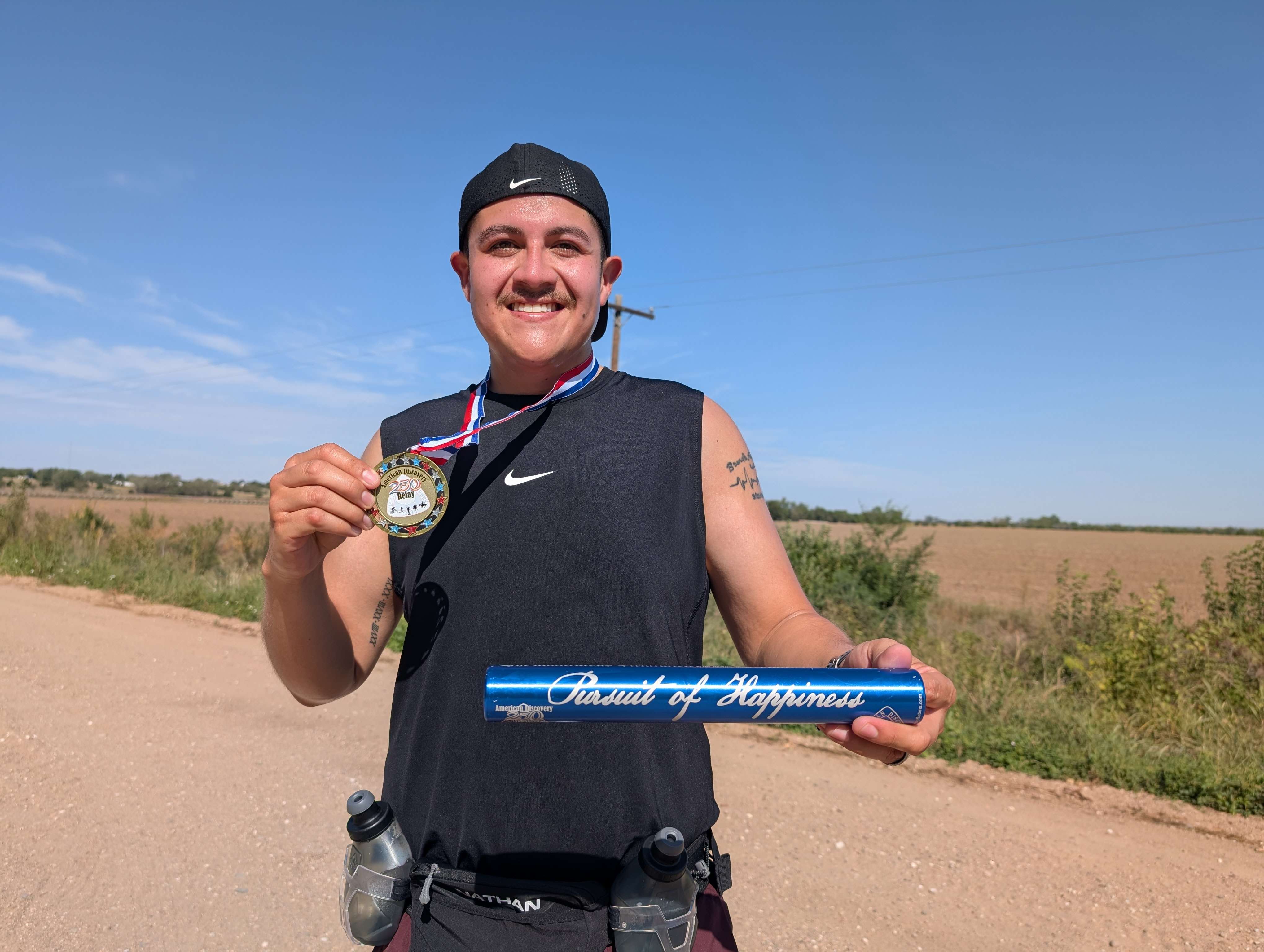 Alcala with his finishers medallion and the patriotic baton that includes a copy of the Declaration of Independence inside. (photo by Mike Courson)