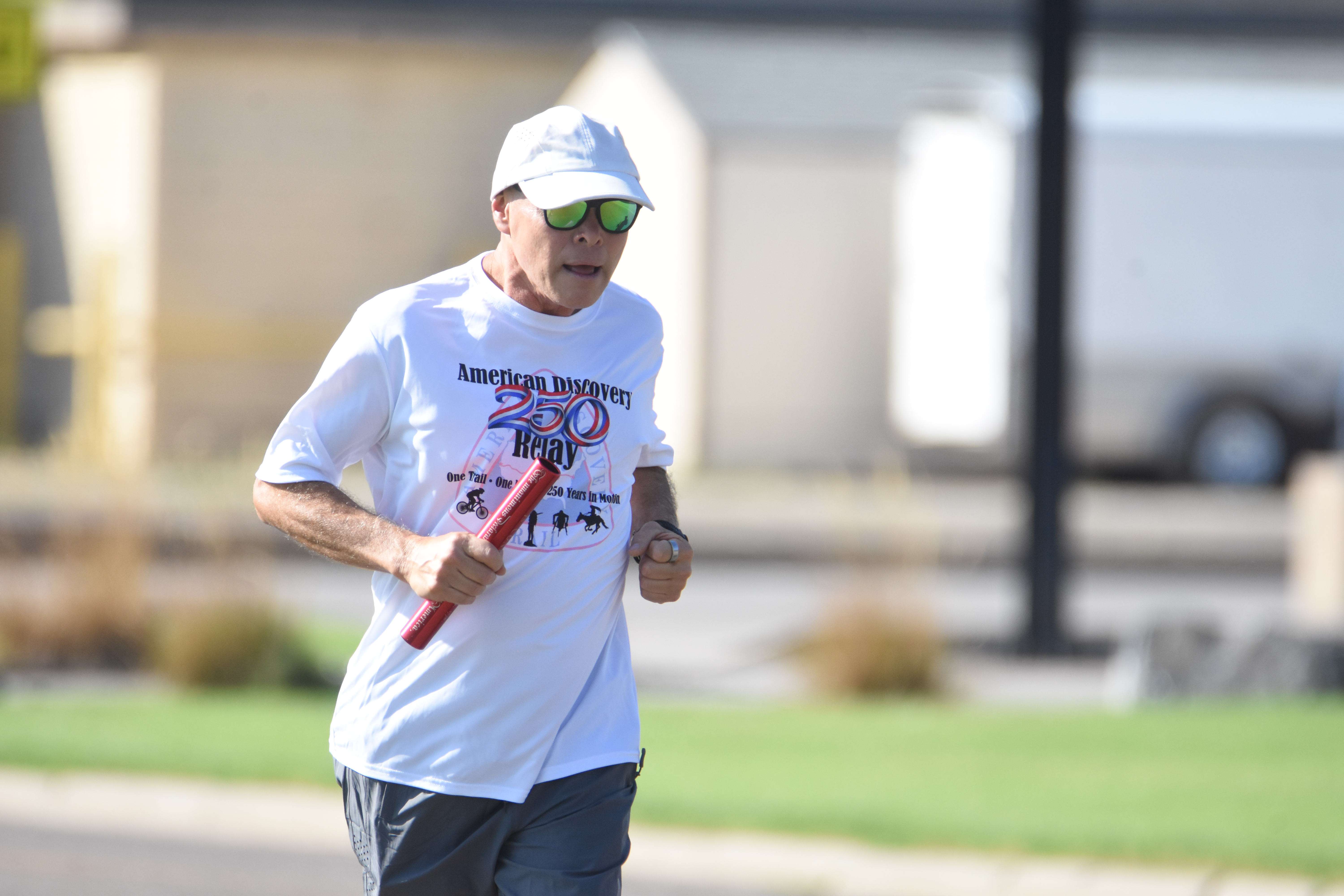 Saenz carries the baton down Main Street during its pass through Great Bend Saturday morning. (photo by Mike Courson)