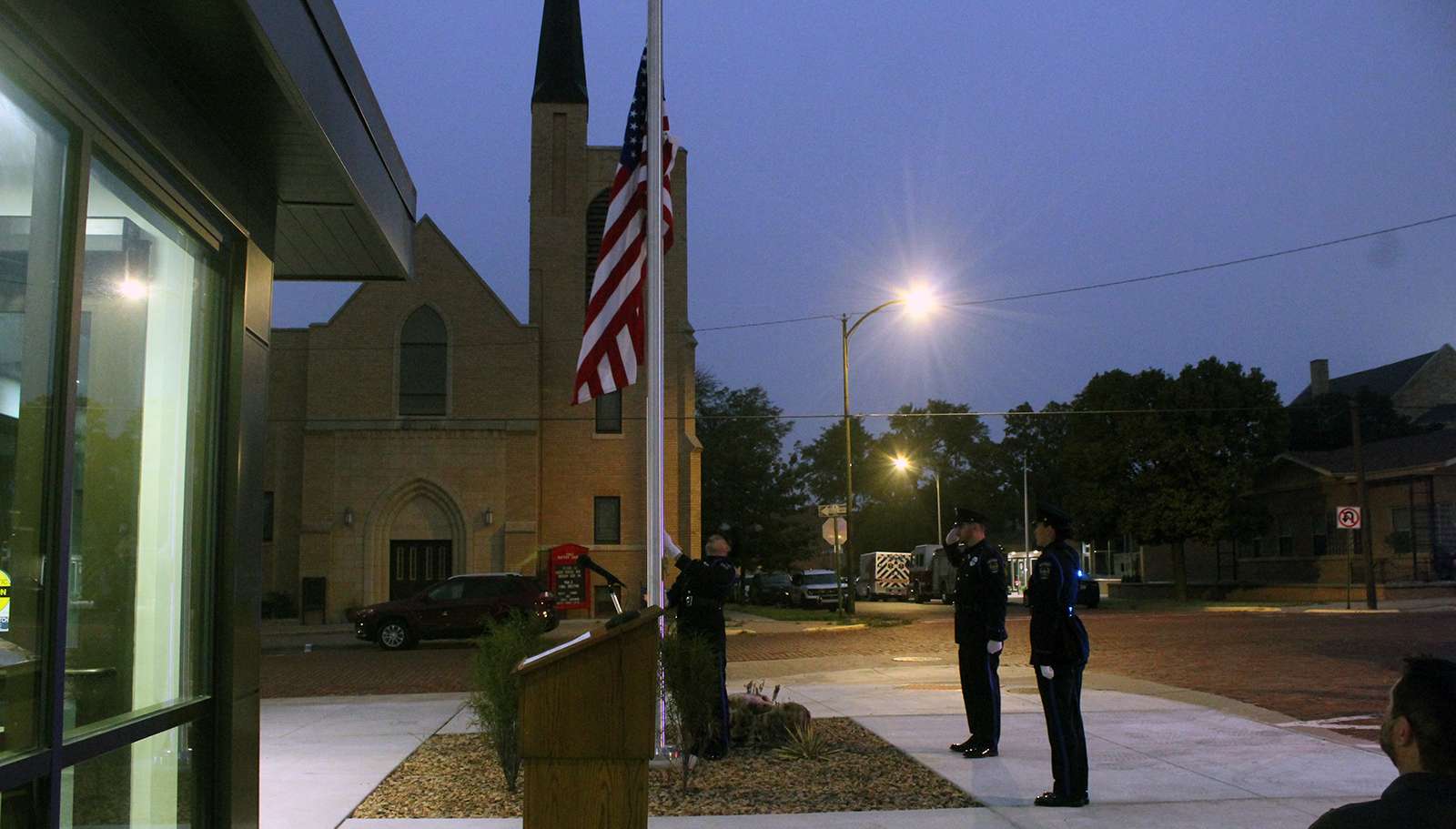 An honor guard lowers a flag to half staff at the new Hays Law Enforcement Center today in honor of fallen Hays Police Sgt. Scott Heimann. He was killed one year ago today responding to a barricaded suspect. Photo by Cristina Janney/Hays Post