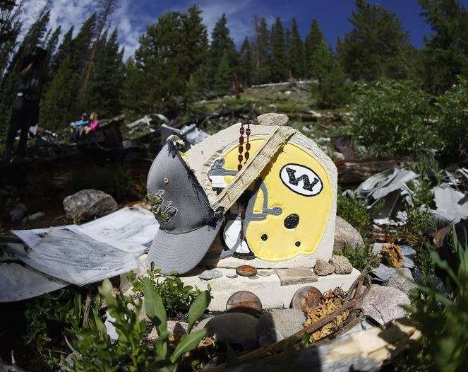 A likeness of the football helmet for the Wichita State Shockers, circa 1970, is draped by a cap as teammates, family members and friends visit the crash site near Loveland Pass Monday, July 27, 2020, west of Silver Plume, Colo. Wreckage from the plane, which was one of two being used to take the Shockers to play a football game against Utah State University in Logan, Utah, is still scattered on the mountain top nearly 50 years after the crash close to the Eisenhower Tunnel. (AP Photo/David Zalubowski)